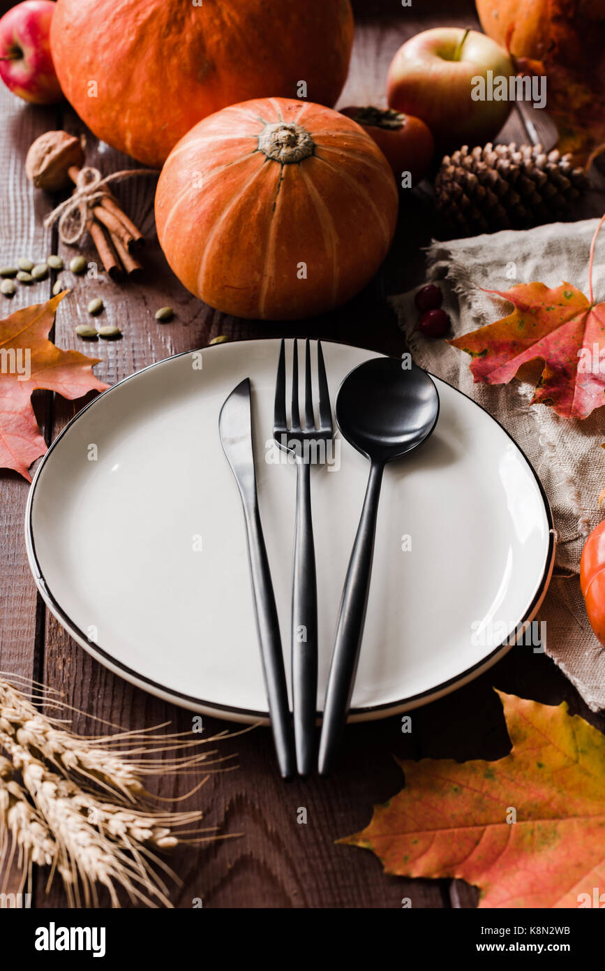 Dîner de thanksgiving de table avec des citrouilles, blé, fallen leaf noir et couverts. composition verticale, selective focus Banque D'Images