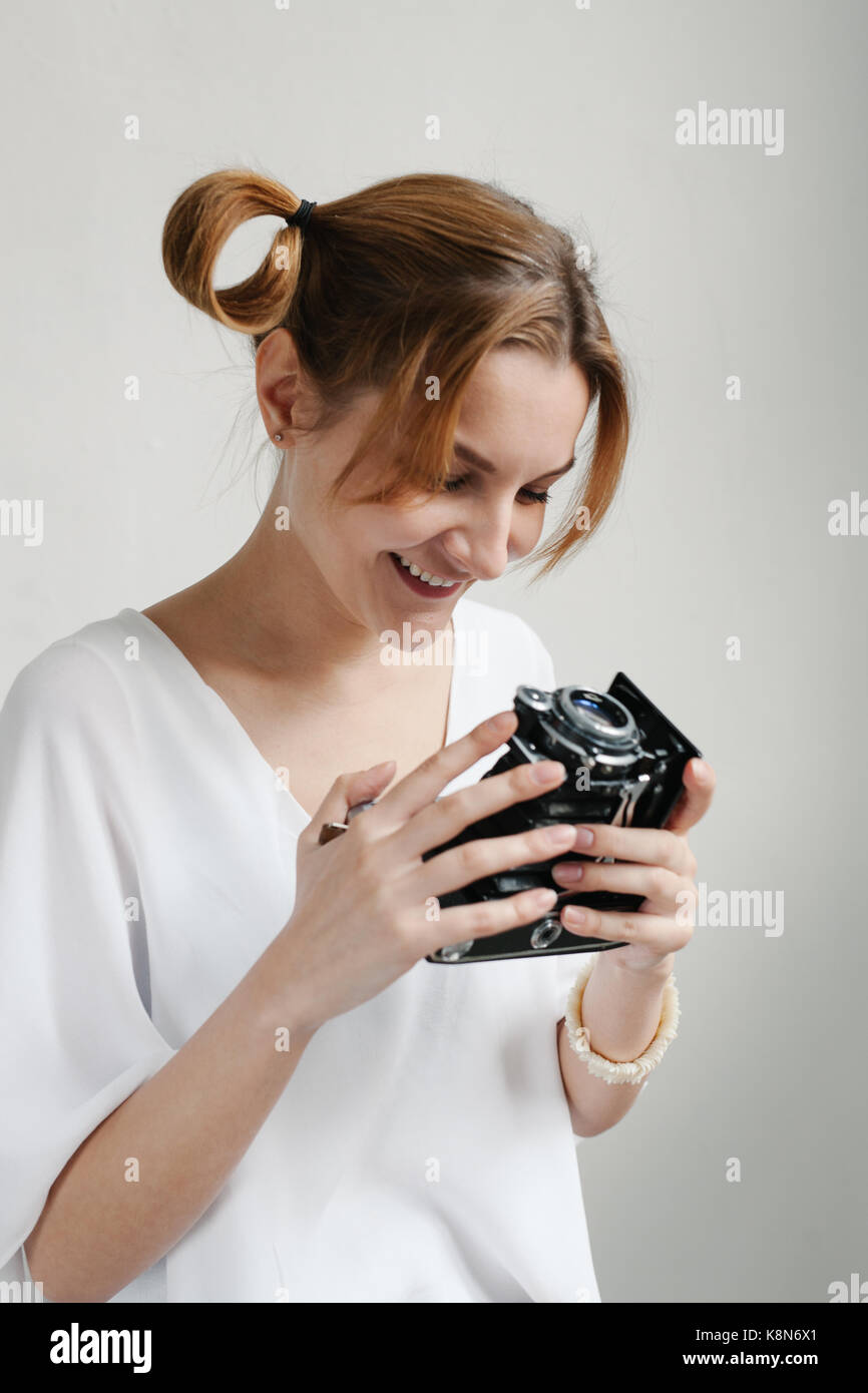 Close up portrait of a smiling pretty girl taking photo sur un appareil photo rétro isolated over white background. Banque D'Images