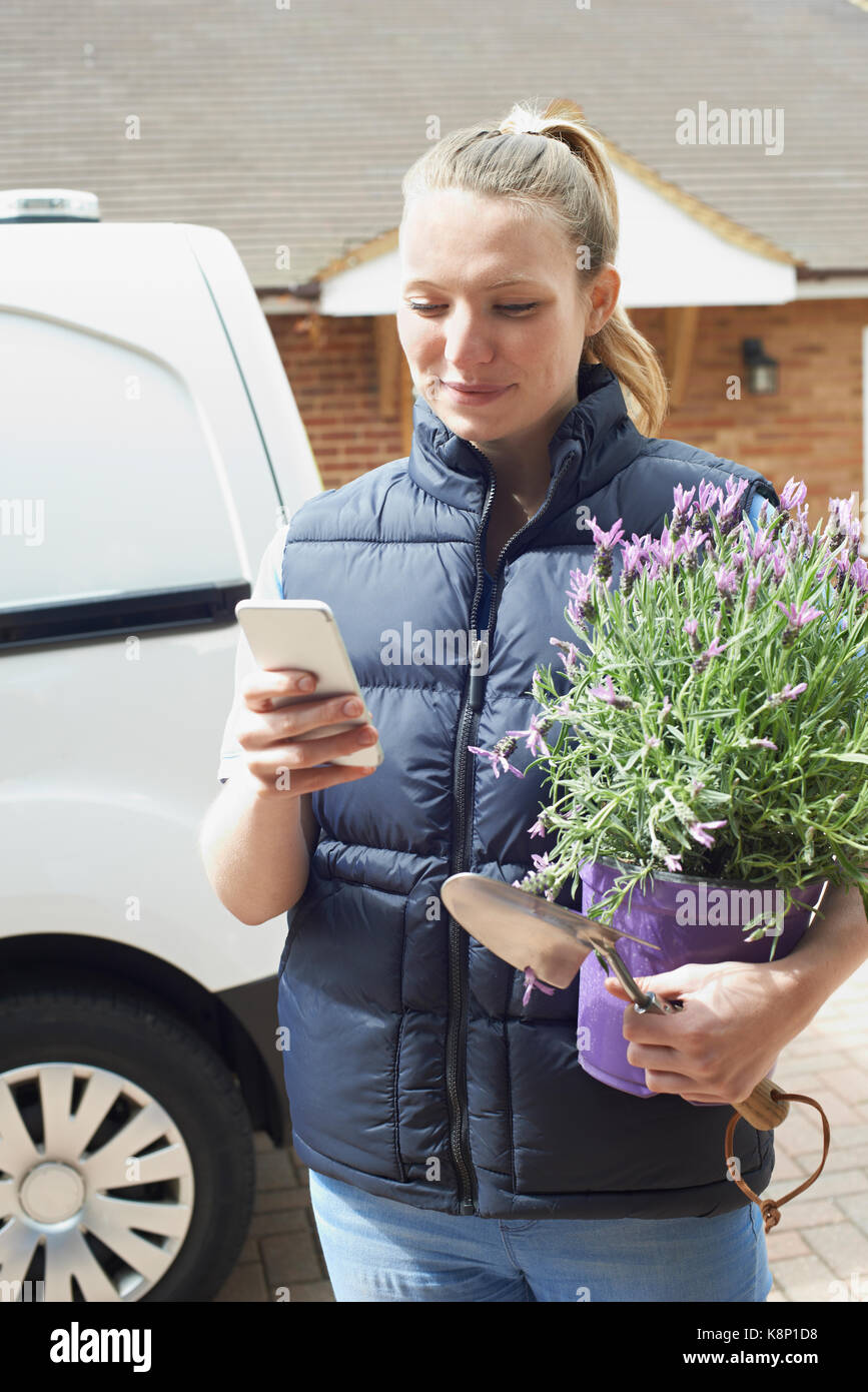 Woman gardening mobile téléphone mobile à l'aide d'affaires Banque D'Images