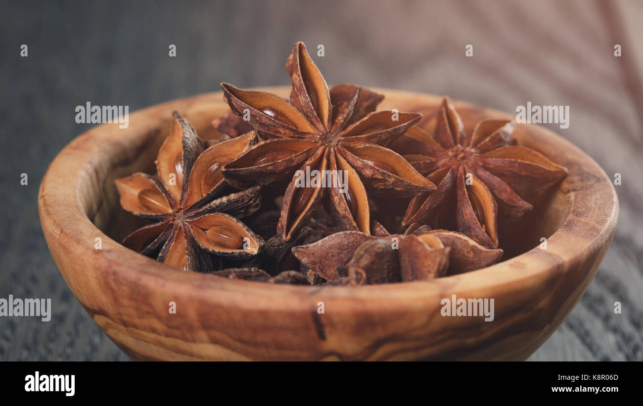Étoiles d'anis dans un bol d'olive sur table en chêne Banque D'Images