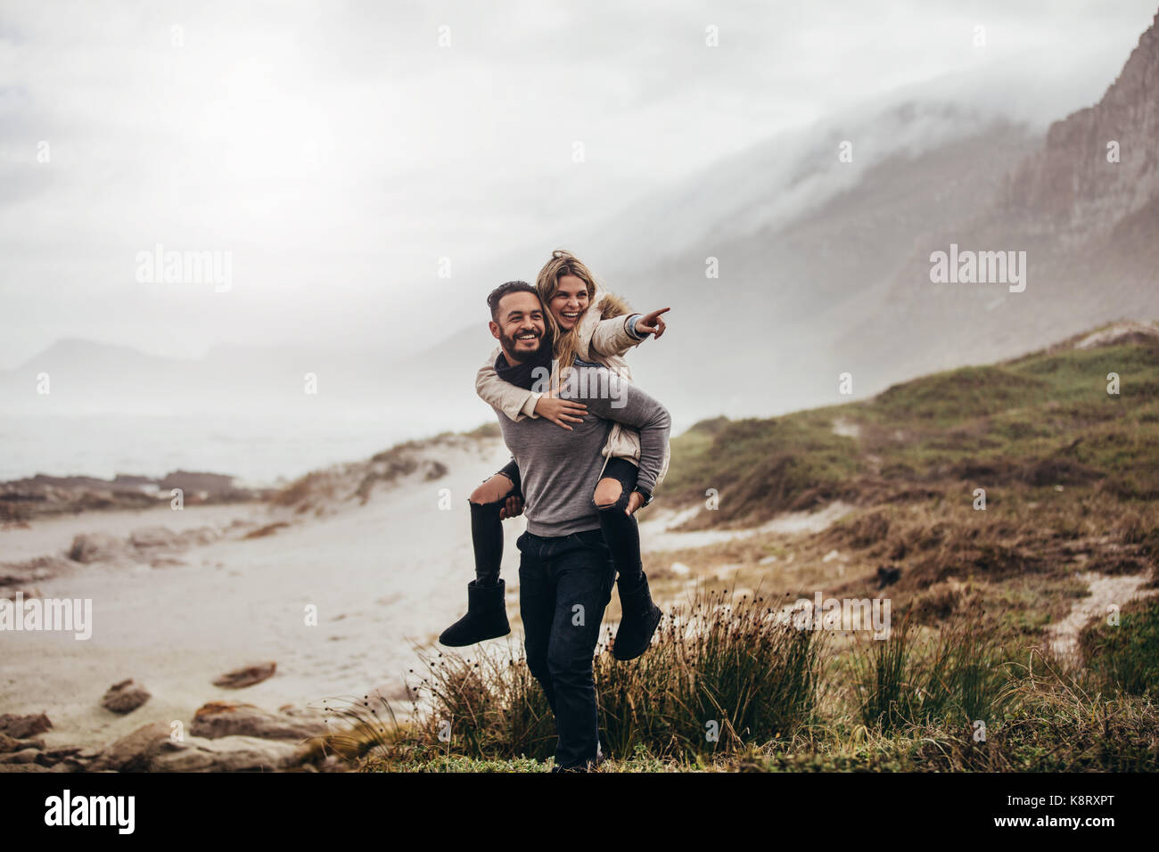 Jeune couple sur le dos le long de la plage, avec femme dirigés à l'écart. L'hiver on beach vacation. Banque D'Images