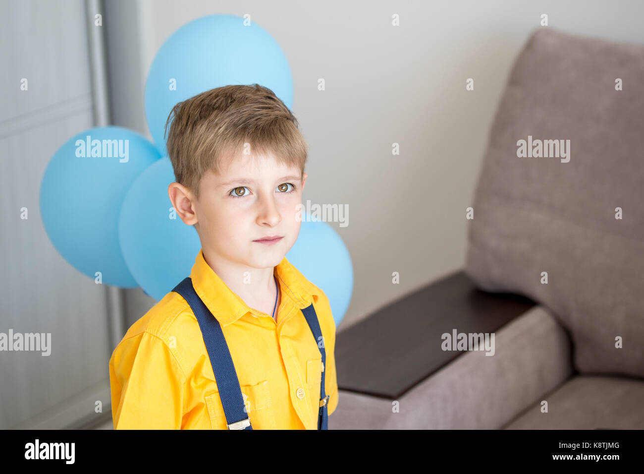 Beau petit bébé garçon caucasien dans des shirt et bretelles félicite un ami holding blue air ballons derrière l'arrière. Banque D'Images