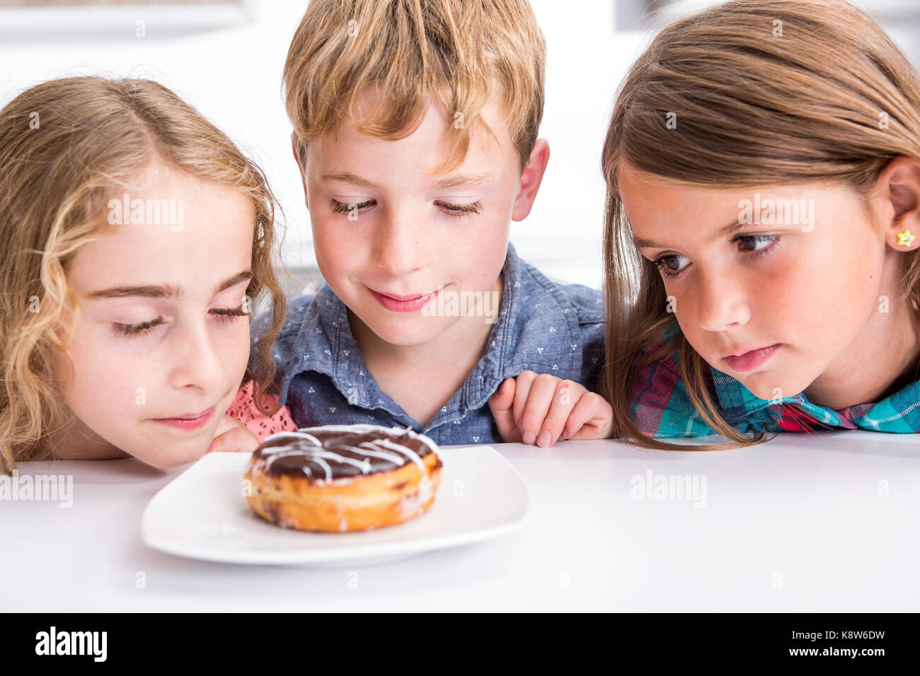 Jeune enfant assis à table watch donut Banque D'Images