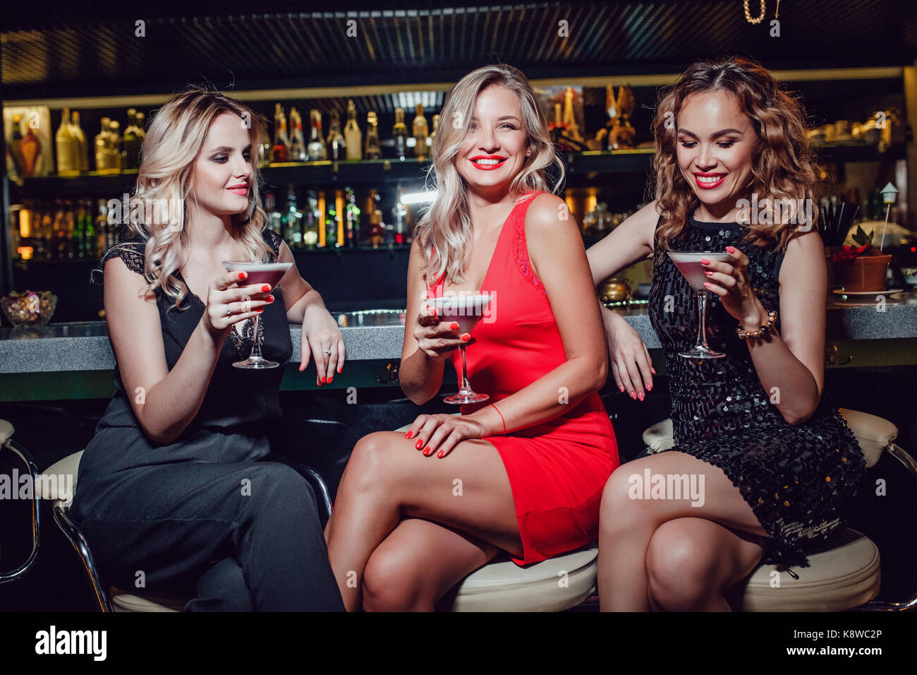 Les belles femmes sont assis sur le bar et de boire des cocktails Photo  Stock - Alamy