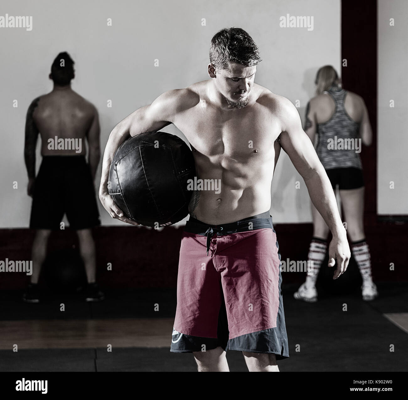Shirtless man holding medicine ball in gym Banque D'Images