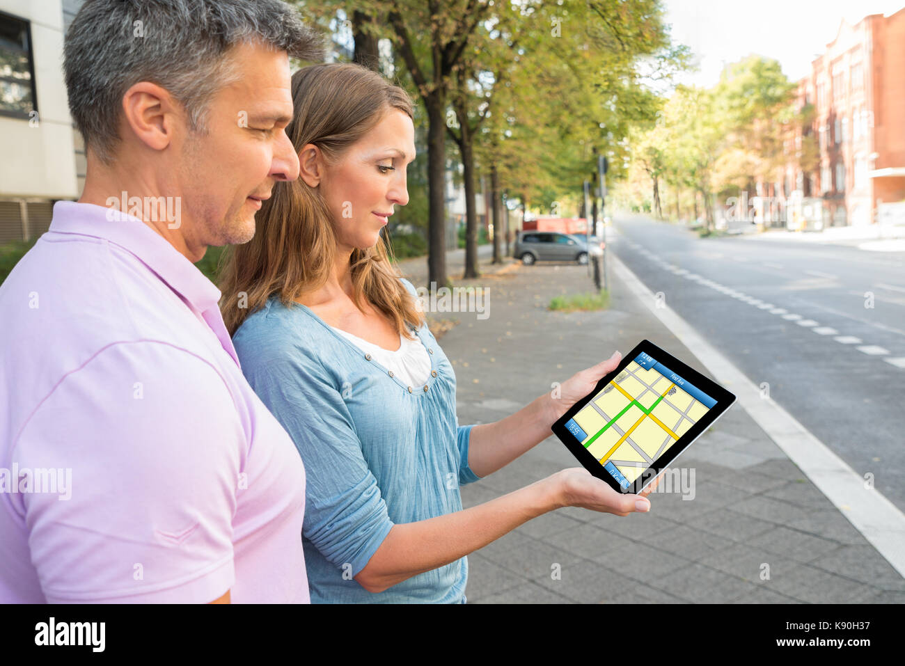 Happy couple looking at digital tablet sur la carte gps Banque D'Images