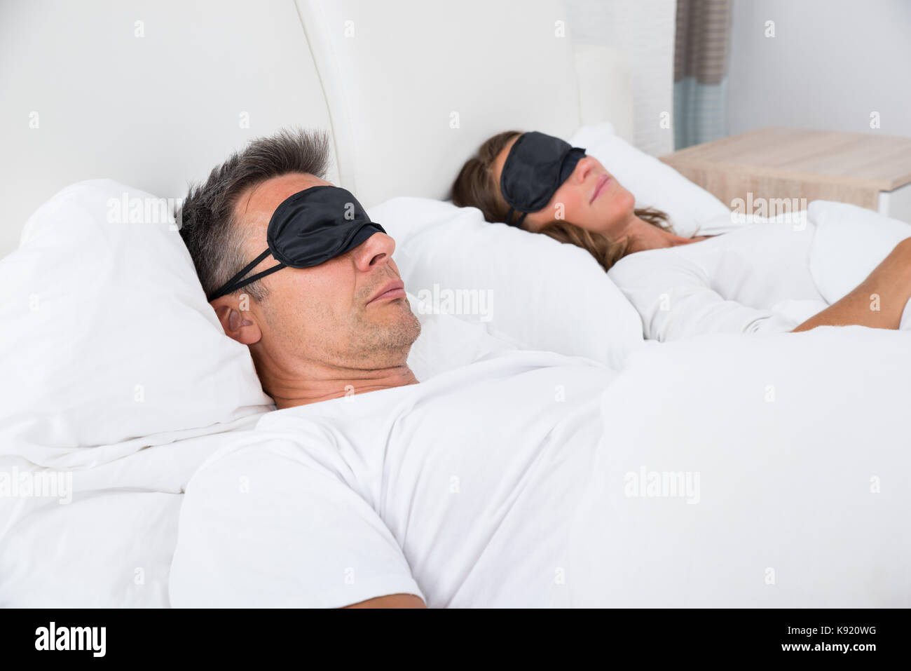 Portrait de mûri Couple confortablement sur lit à l'aide de masque pour les yeux Banque D'Images