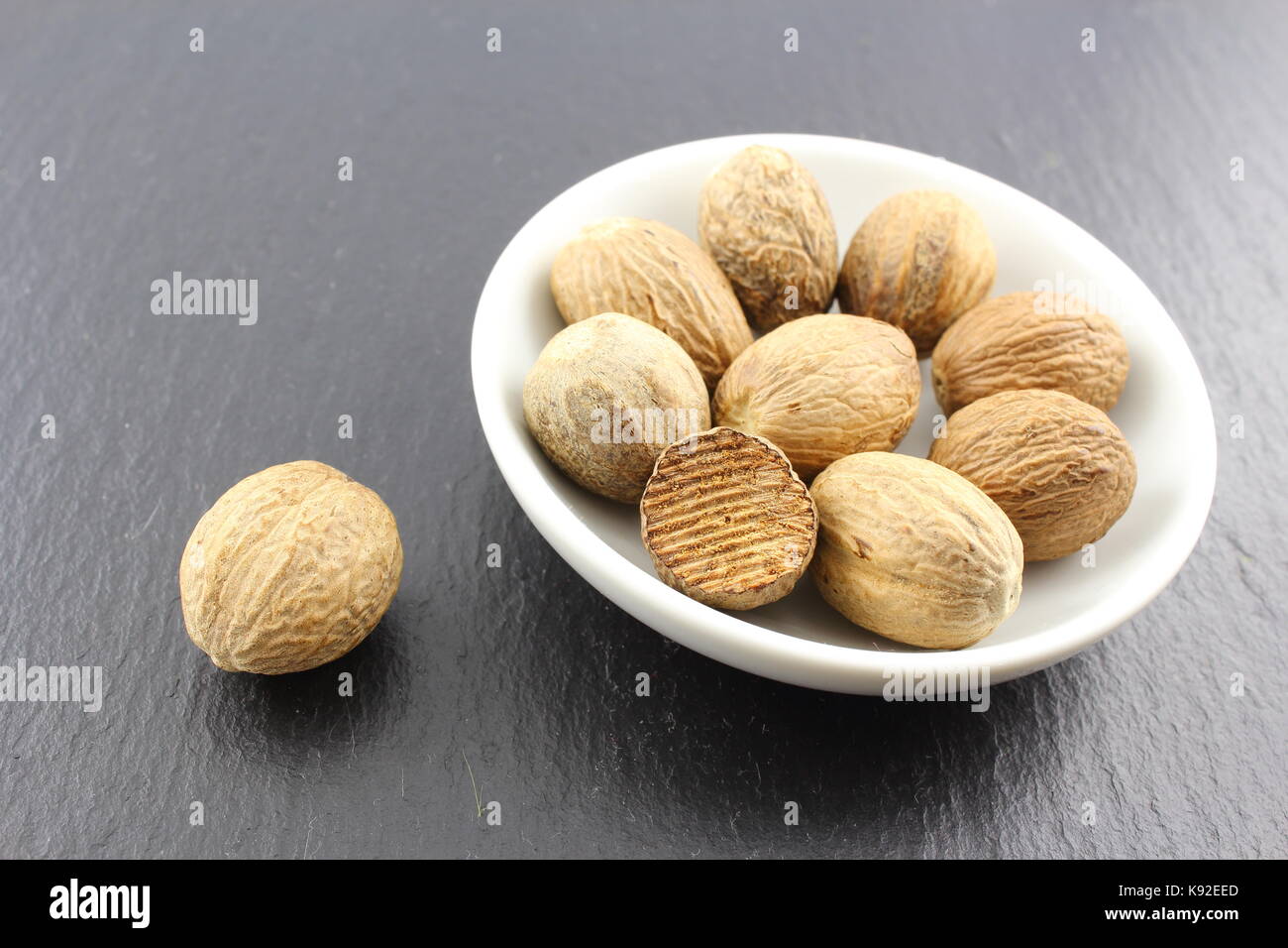 Composition de la muscade graines dans un petit bol blanc Banque D'Images