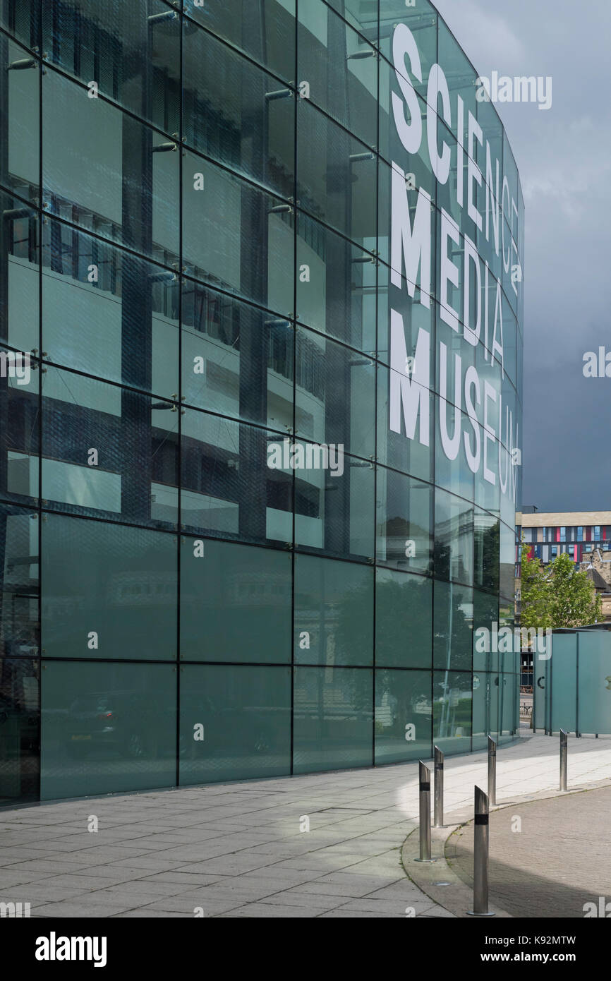 Contre un ciel gris foncé, vue extérieure du Musée des sciences et des médias (Bradford, West Yorkshire, England, UK) avec d'impressionnants, courbe, façade vitrée. Banque D'Images