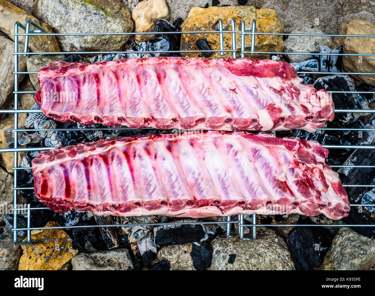 Décisions sur des côtes de porc barbecue improvisé fait maison barbecue. décisions churrasco sur un feu de charbon, briquettes, barbecue dans le sable avec des roches et des pierres o Banque D'Images