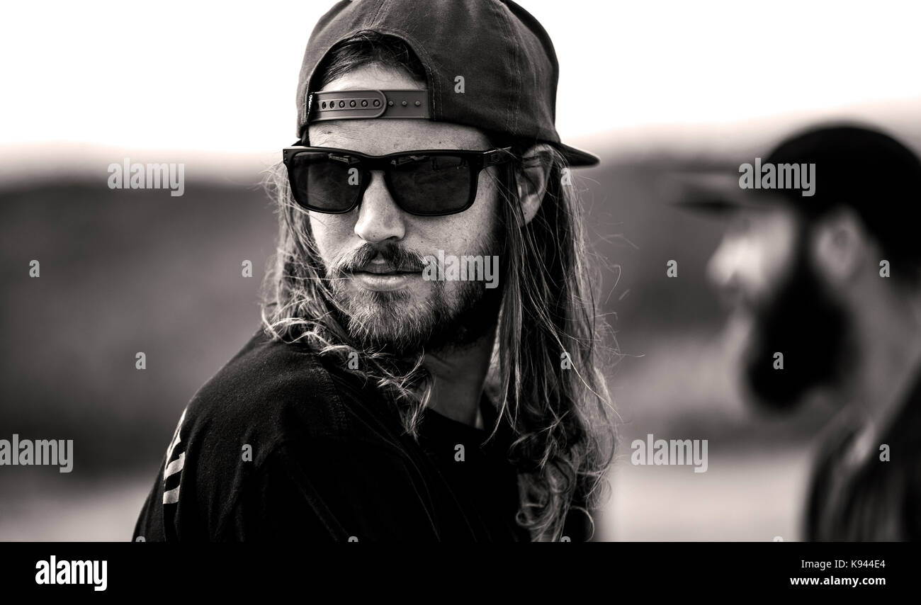 Portrait d'homme barbu avec les cheveux longs, portant des lunettes de  soleil et chapeau de base-ball face à l'arrière Photo Stock - Alamy