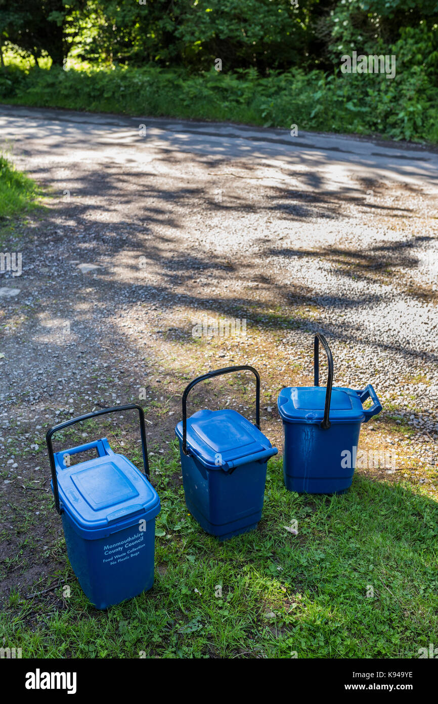 Des poubelles en plastique bleu collection en attente sur une étroite route de campagne monmouthshire, Wales. Banque D'Images