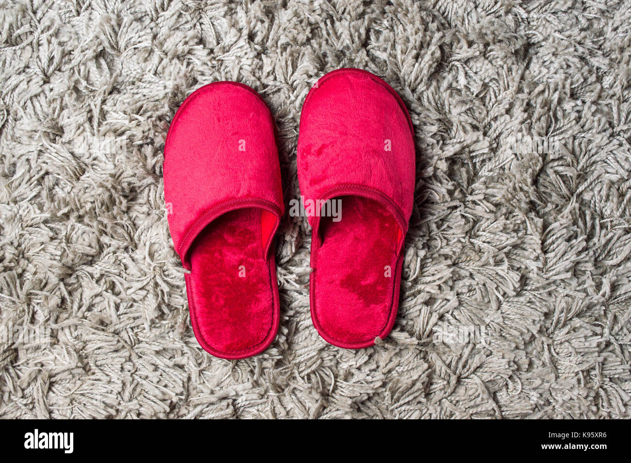 Maison Rouge chaussons sur tapis gris moelleux Banque D'Images