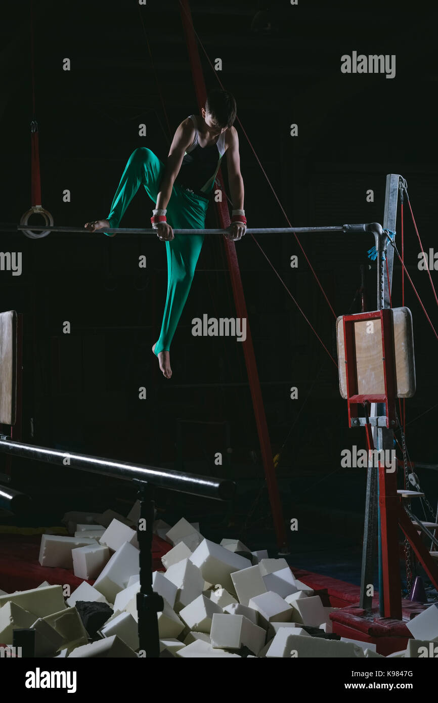 La pratique de la gymnastique gymnaste masculin sur la barre horizontale dans la salle de sport Banque D'Images