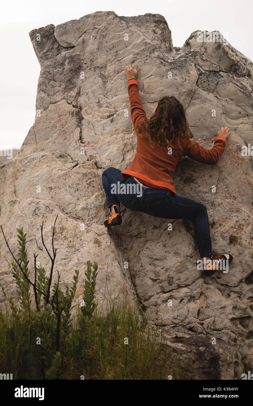 Vue arrière de la falaise d'escalade femme lors d'une journée ensoleillée Banque D'Images