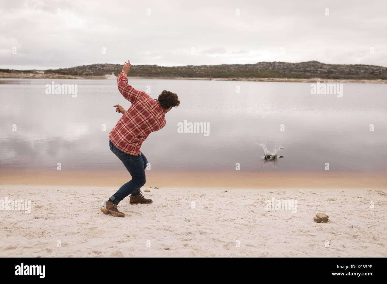 Man throwing pierre dans la rivière sur une journée ensoleillée Banque D'Images