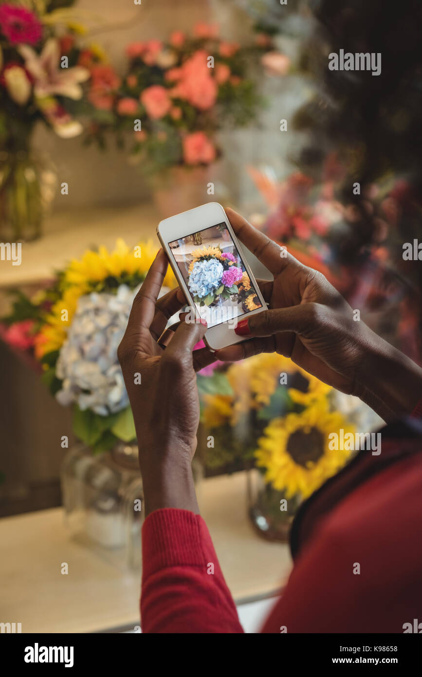 Close-up of female florist taking photograph on mobile phone de bouquet de fleurs Banque D'Images