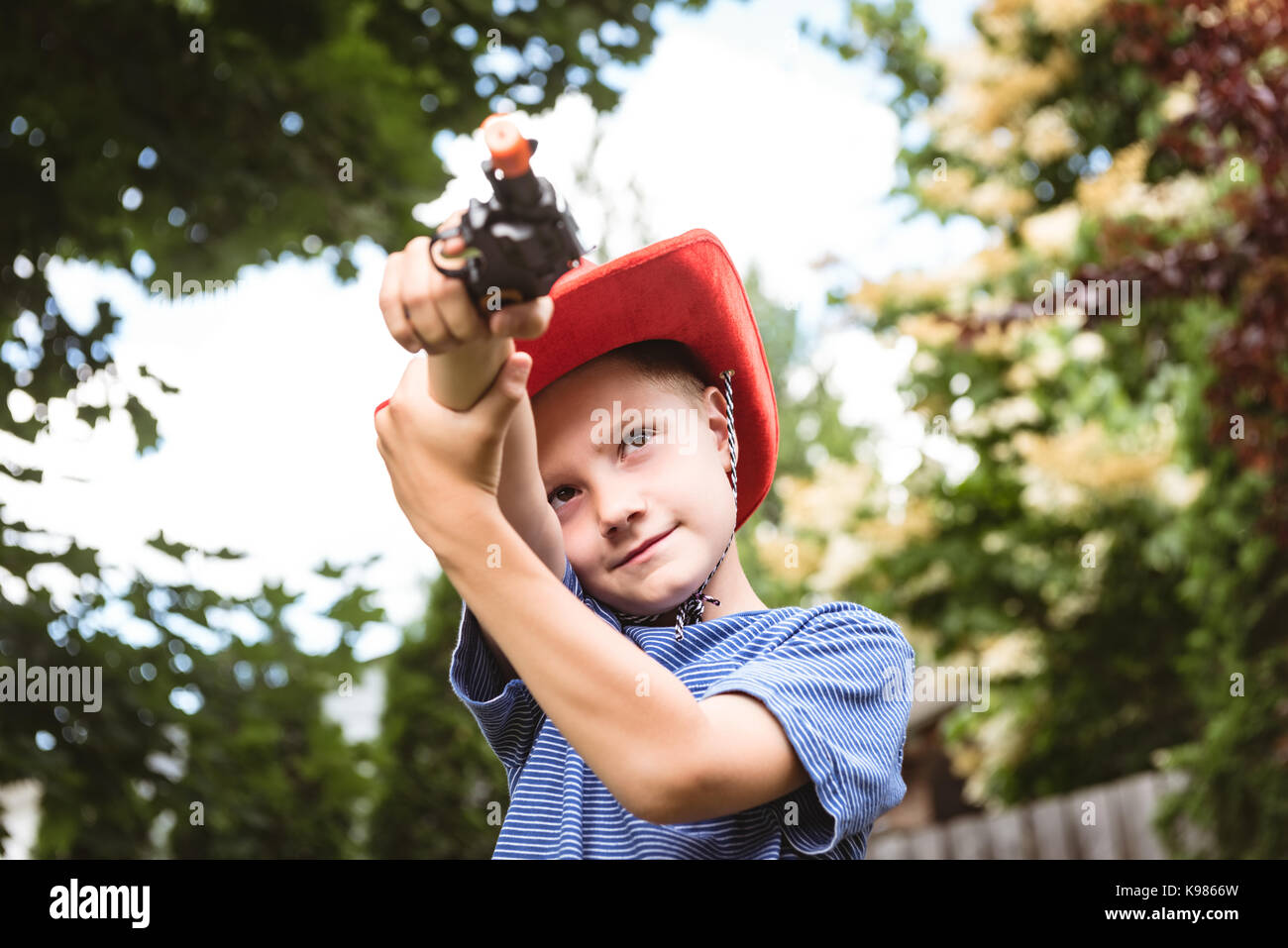 Cute boy faisant semblant d'être un cowboy in playground Banque D'Images Cute boy faisant semblant d'être un cowboy in playground Banque D'Images