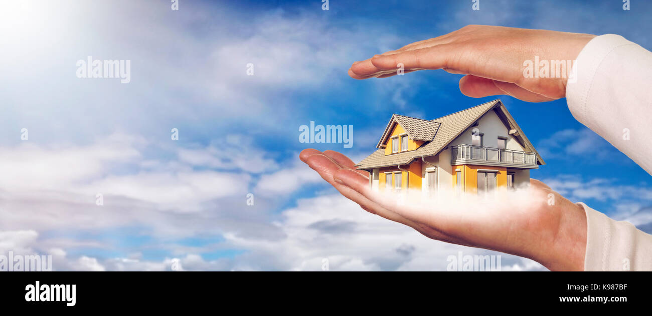 Maison sur les mains devant un ciel bleu avec des nuages Banque D'Images