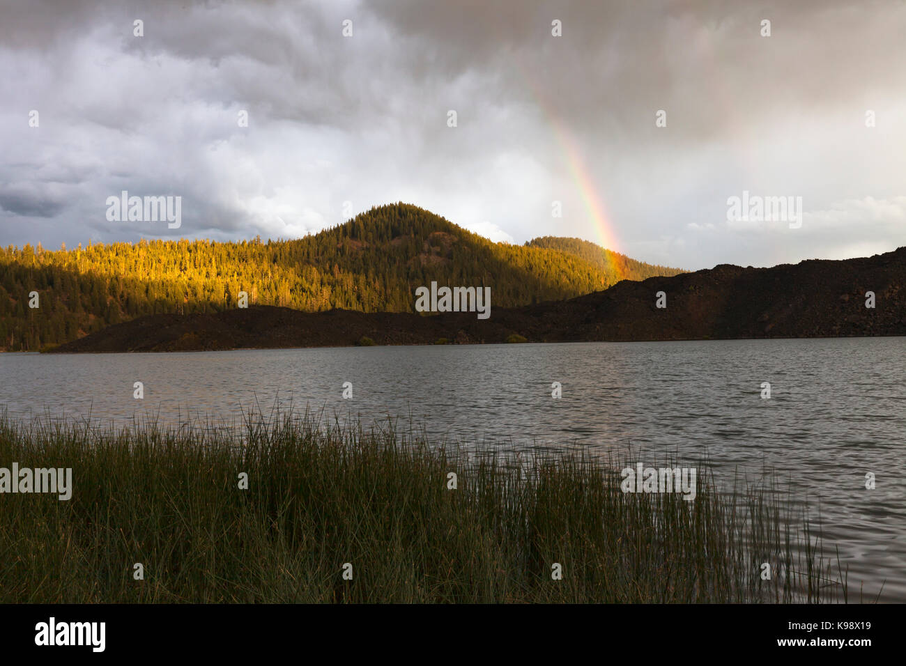 Un arc-en-ciel s'élève au-dessus du champ de lave sur la rive sud du lac Butte dans Lassen Volcanic National Park. Banque D'Images