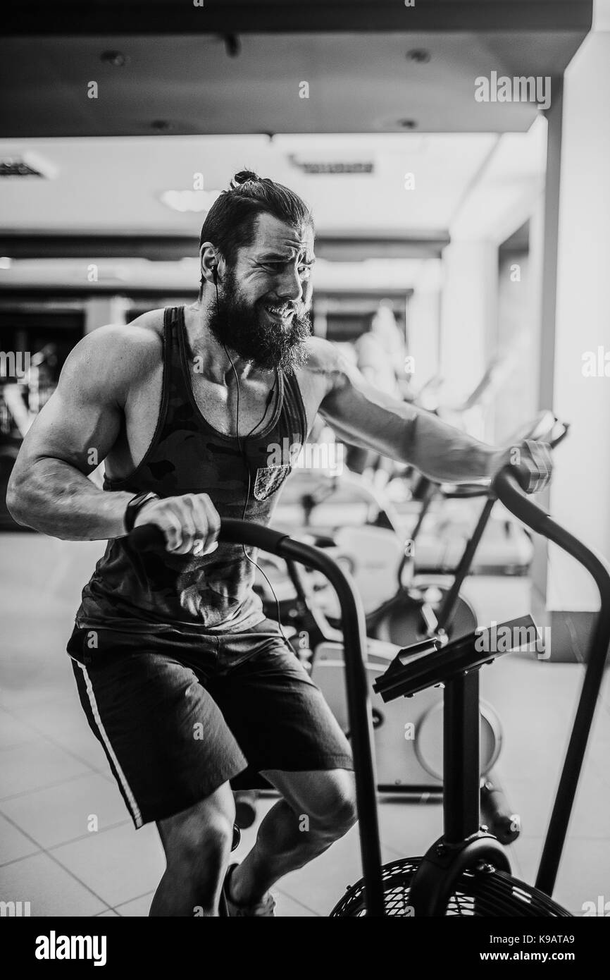 Jeune homme à l'aide d'un vélo d'exercice dans la salle de sport fitness en utilisant de l'air mâle. vélo pour entraînement cardio Gym crossfit à. Banque D'Images