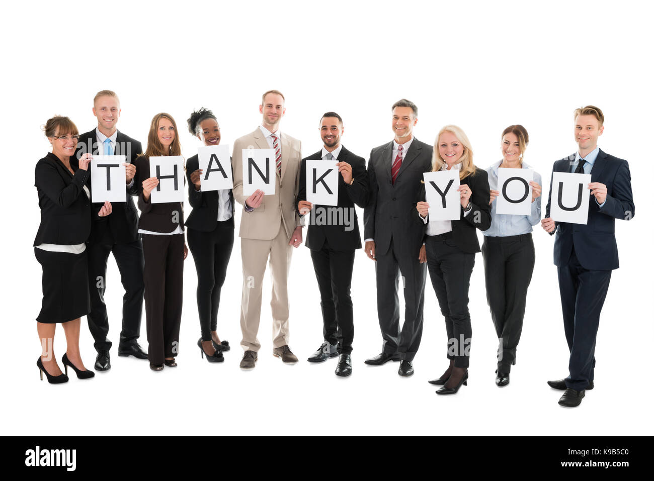 Full Length portrait of smiling business team holding merci sign against white background Banque D'Images