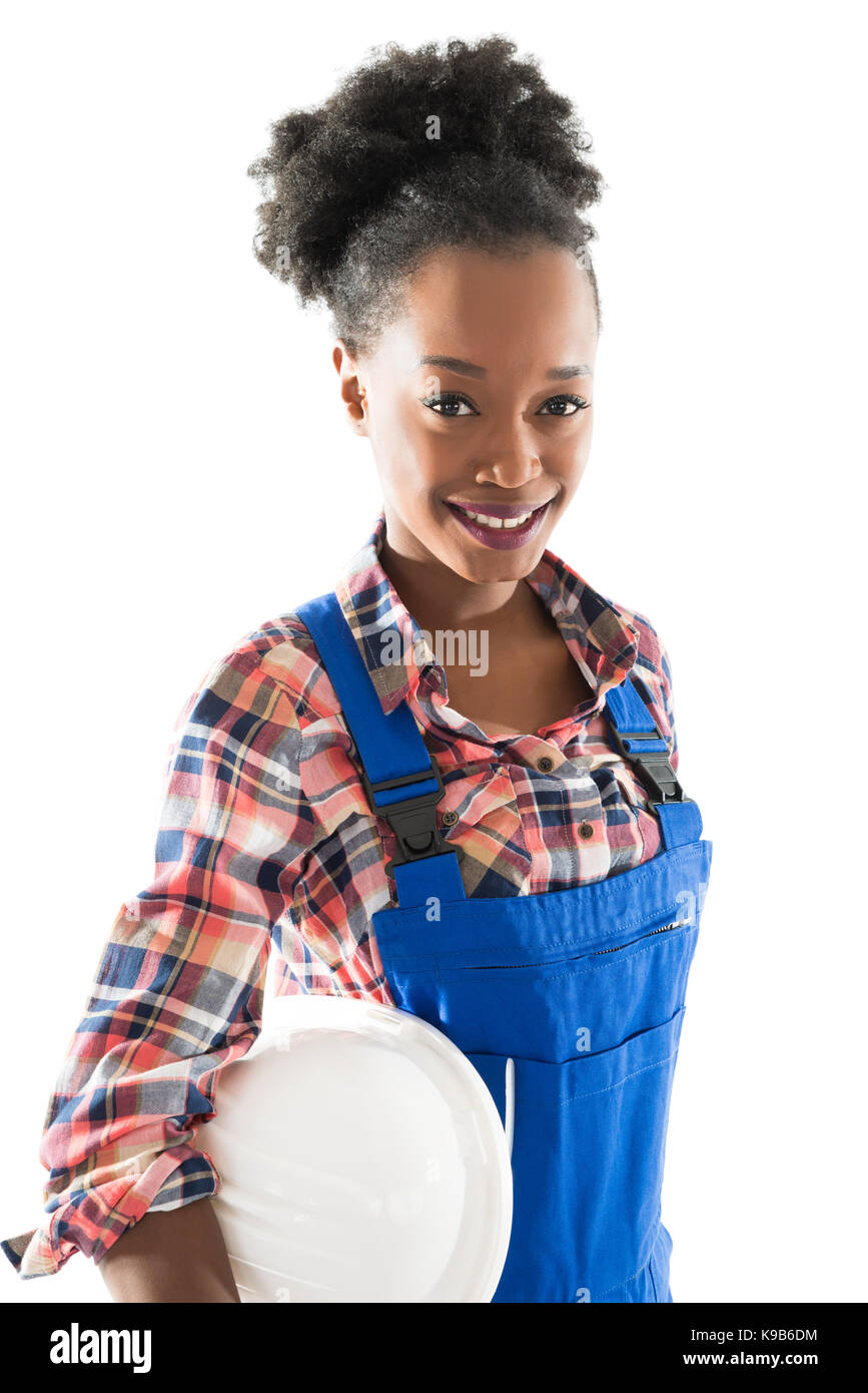 Portrait of smiling female carpenter holding hardhat standing against white background Banque D'Images