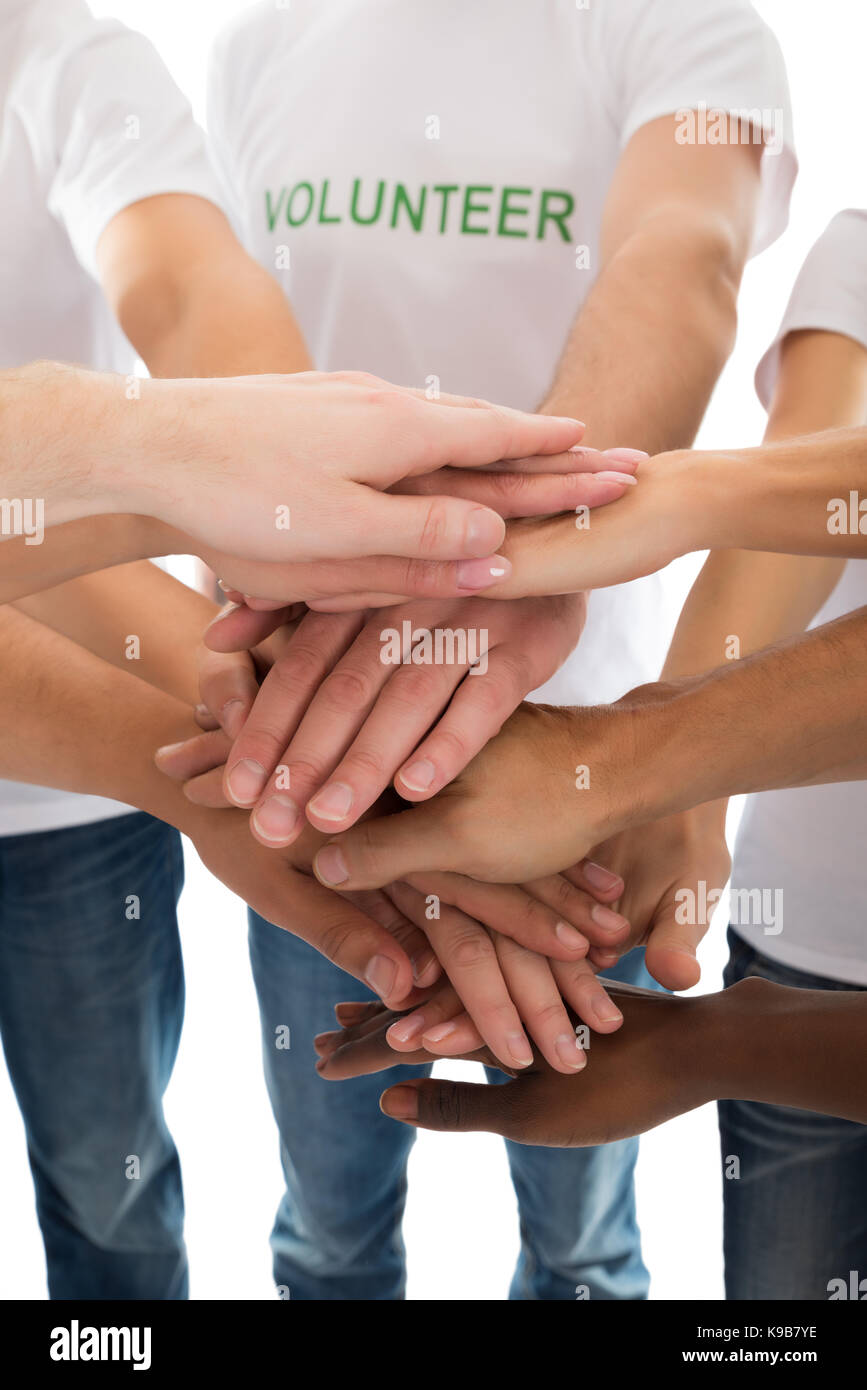 Portrait de bénévoles multiethnique piling mains contre fond blanc Banque D'Images