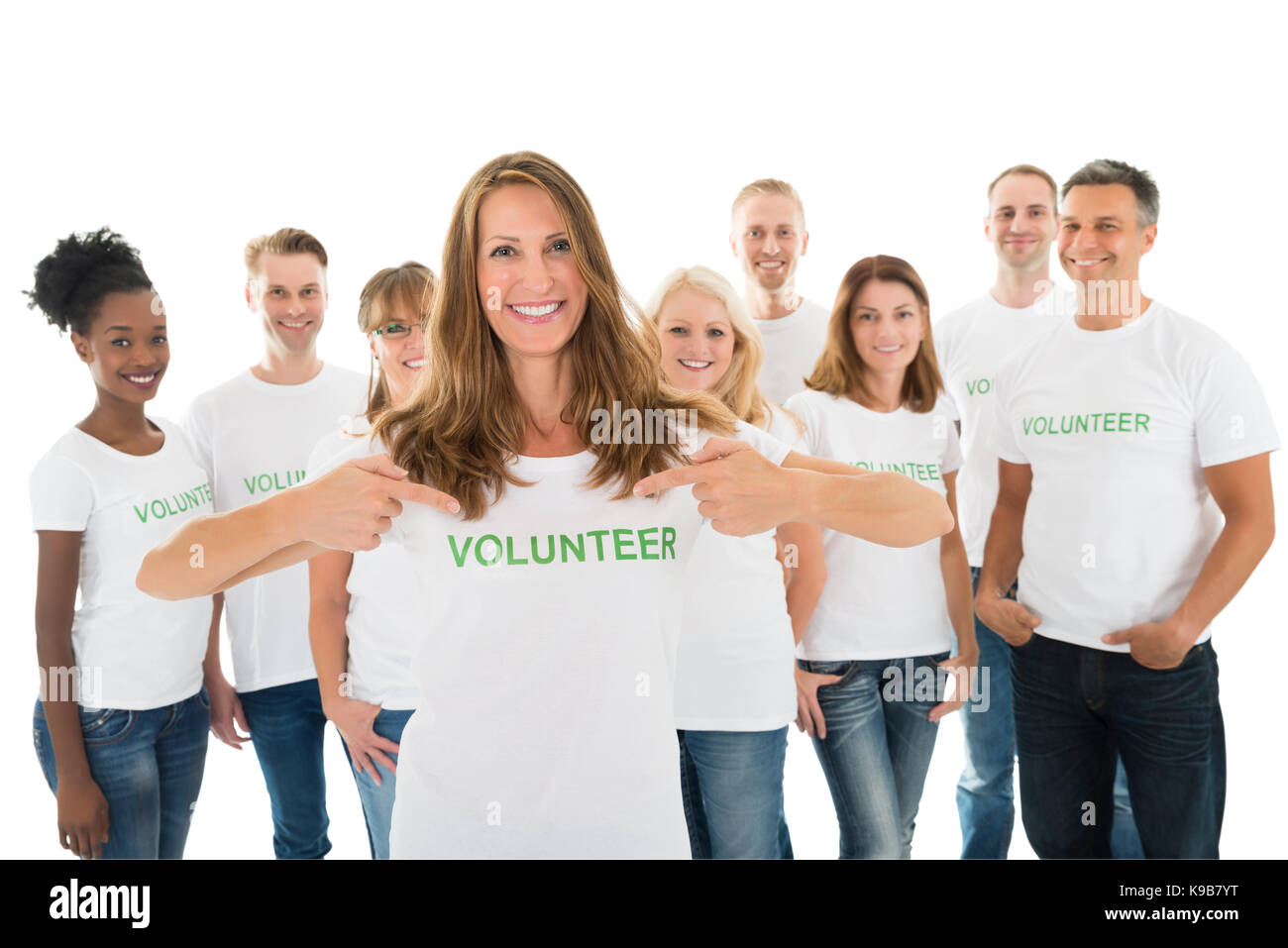 Portrait of happy woman showing volunteer texte sur tshirt avec friends standing over white background Banque D'Images