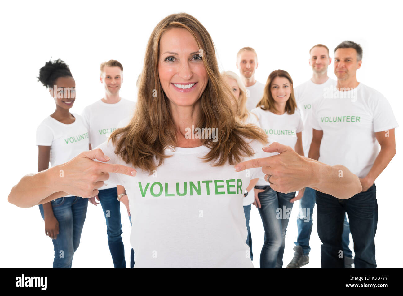 Portrait of happy woman showing volunteer texte sur tshirt avec friends standing over white background Banque D'Images