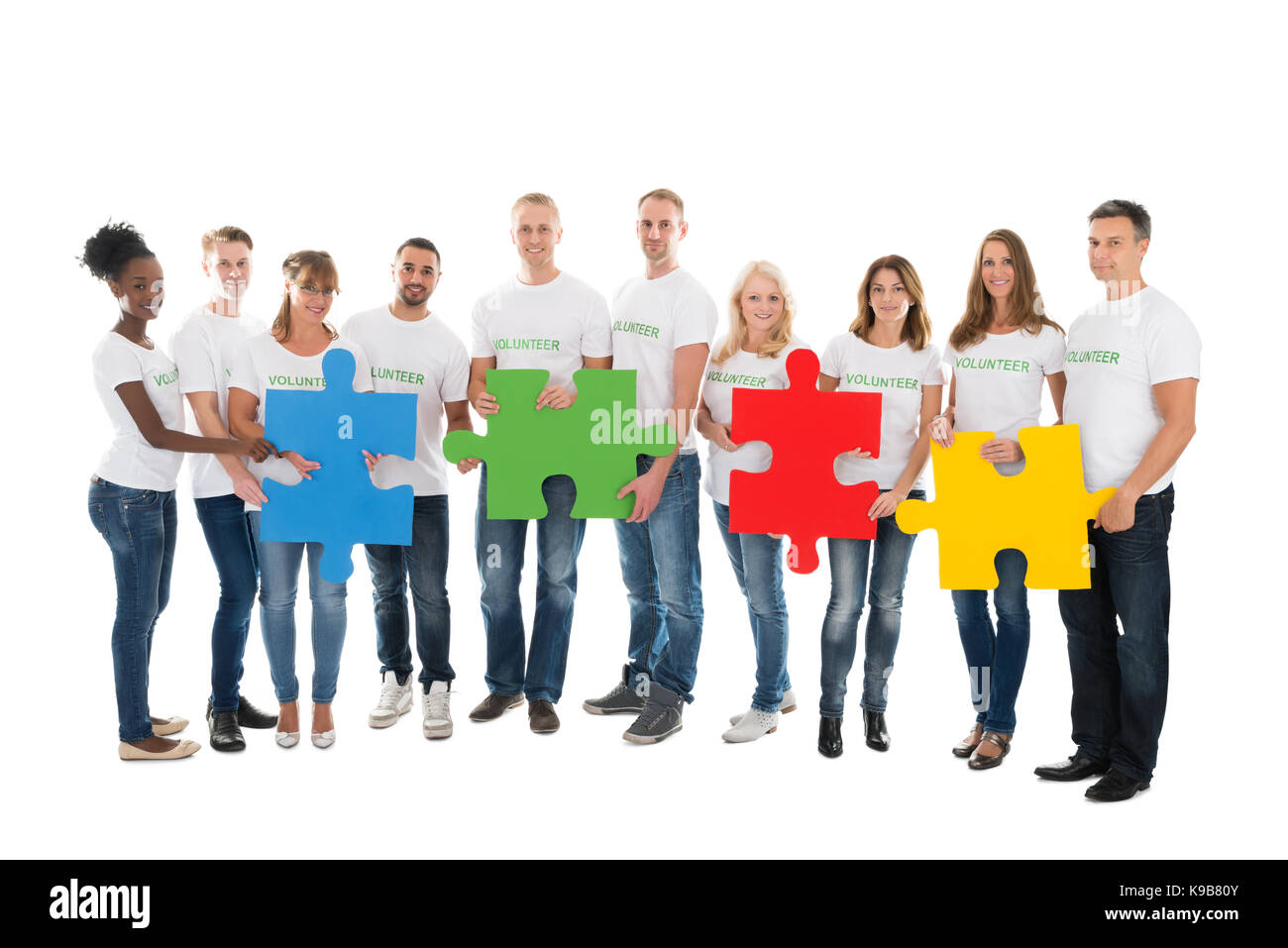 Portrait de certains bénévoles holding jigsaw pieces contre fond blanc Banque D'Images