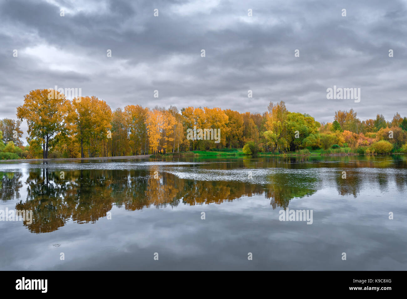 Le lac, reflétant le ciel nuageux et feuillage d'automne des arbres sur la rive Banque D'Images