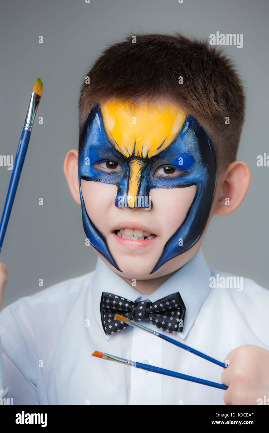 Petit garçon comme Batman peint sur un fond gris. peinture sur visage Banque D'Images