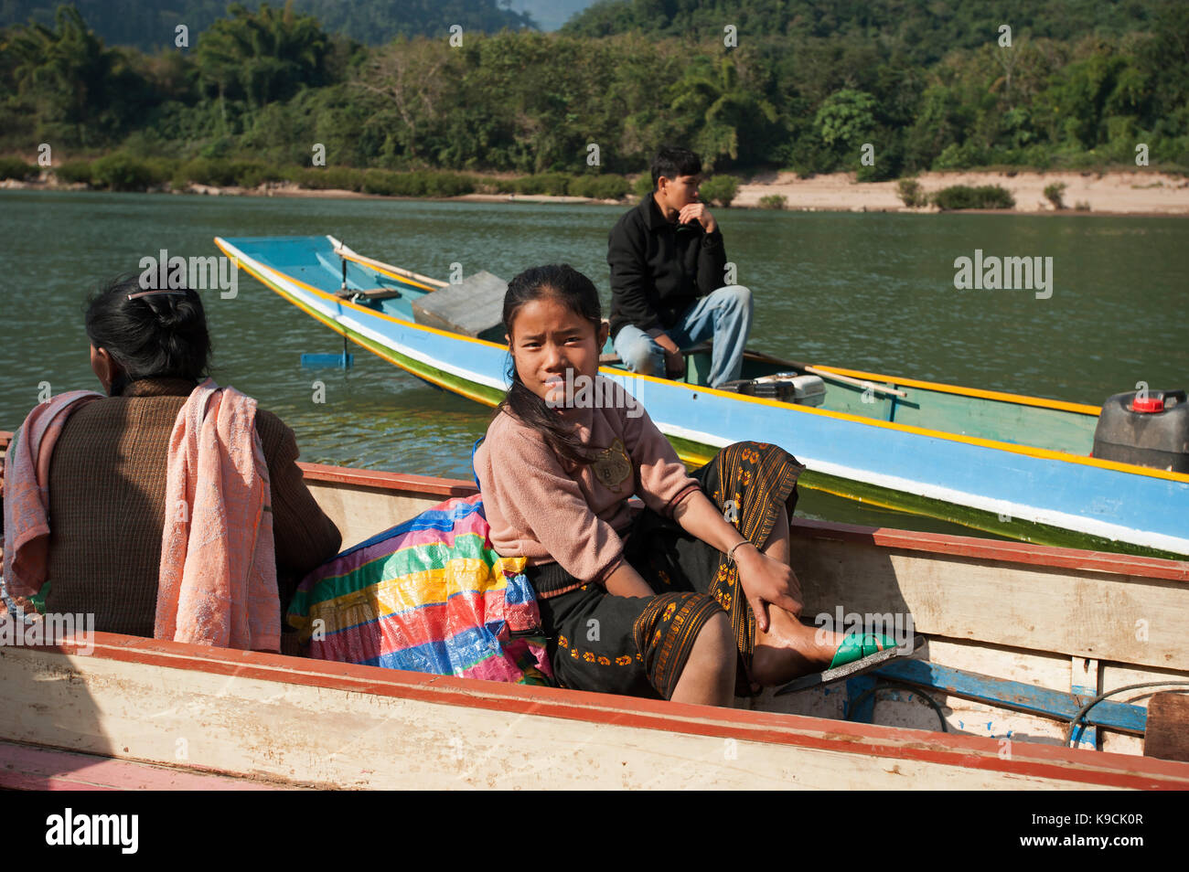 Une jeune fille laotienne est assis dans une rivière canoë avec les montagnes derrière à Muang Ngoi Laos Banque D'Images