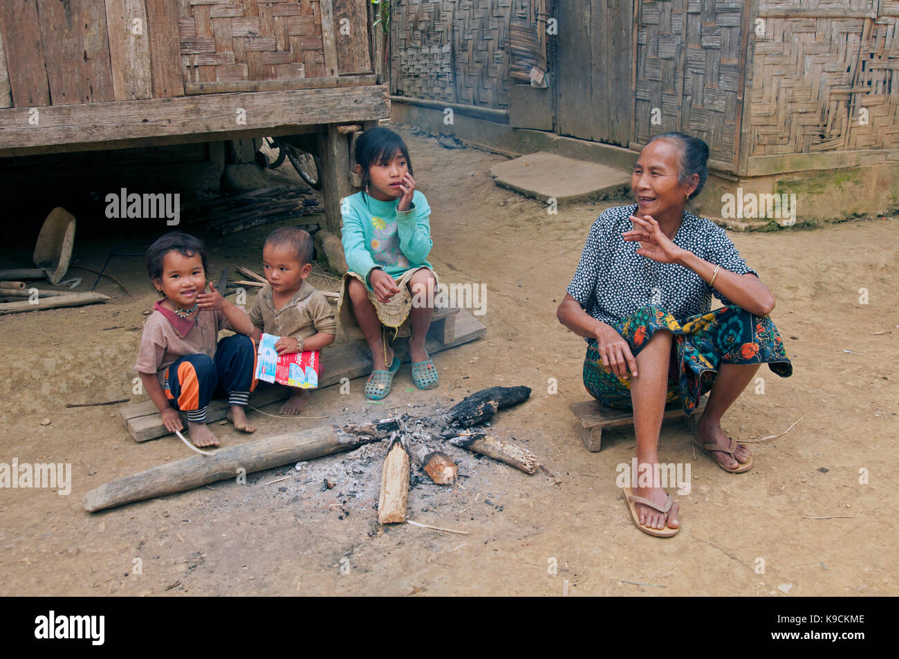 Une vieille femme laotienne s'assoit à côté de trois petits enfants laotiens dans un village rural dans le Nord du Laos Banque D'Images