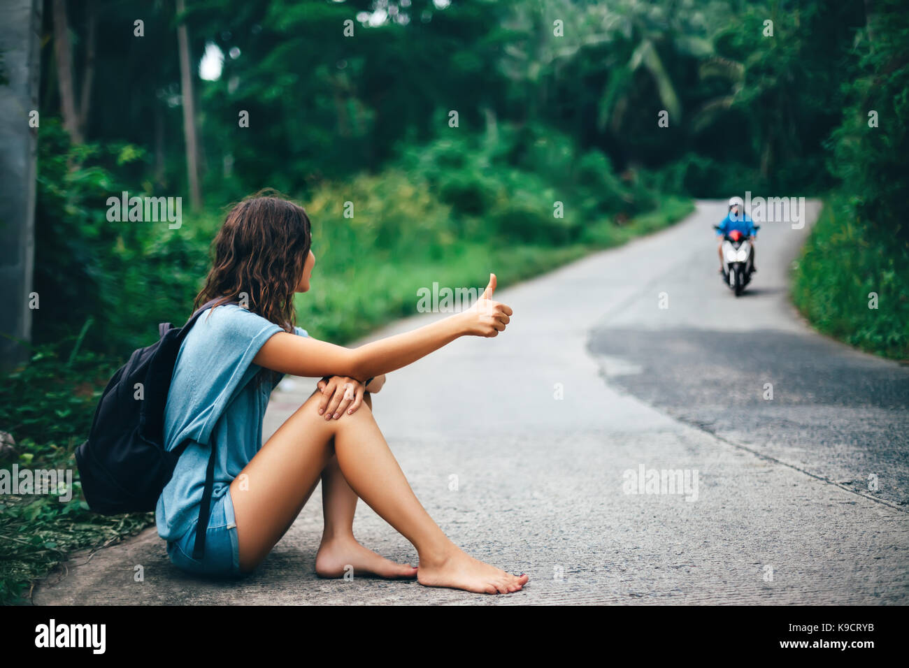 Belle Jeune femme assise sur l'auto-stop road travel concept pieds nus  Photo Stock - Alamy