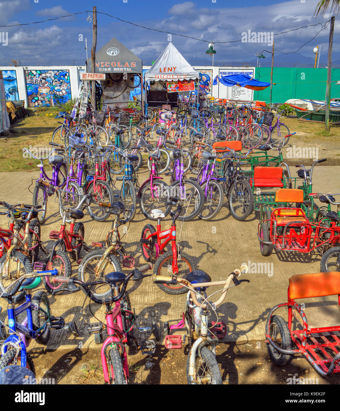 Le rendu HDR de bicyclettes, tricycles colorés et yachts à louer aux touristes à l'établissement Baywalk, Puerto Princesa, Palawan, Philippines. Banque D'Images