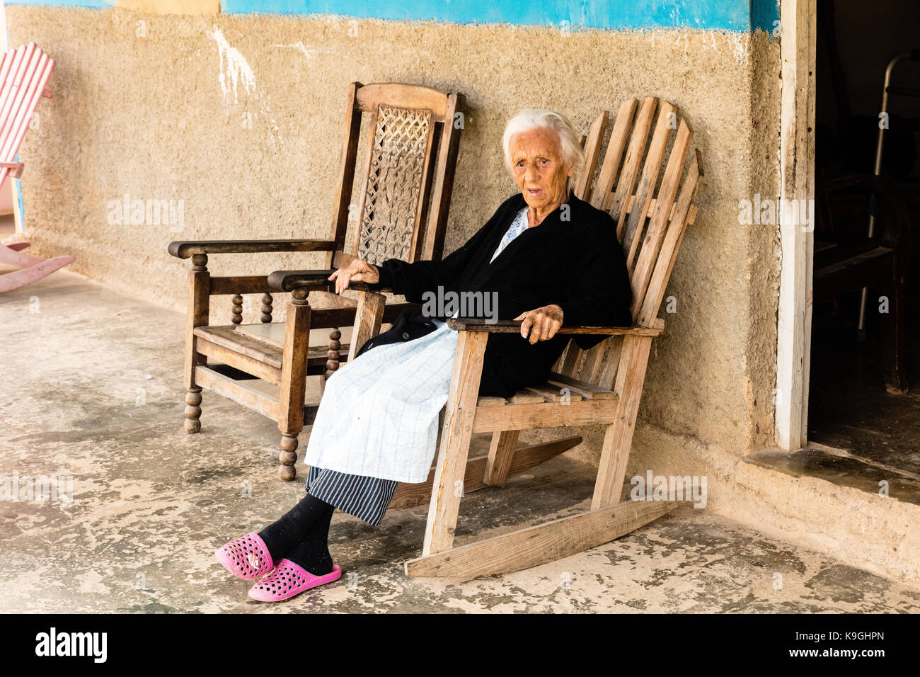Vieille dame aux cheveux blanc souriant assis sur une chaise à bascule en bois à l'extérieur de sa maison, Vinales, Cuba Banque D'Images
