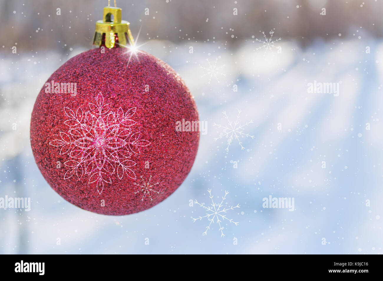 Flocons sur rouge boule de noël Banque D'Images