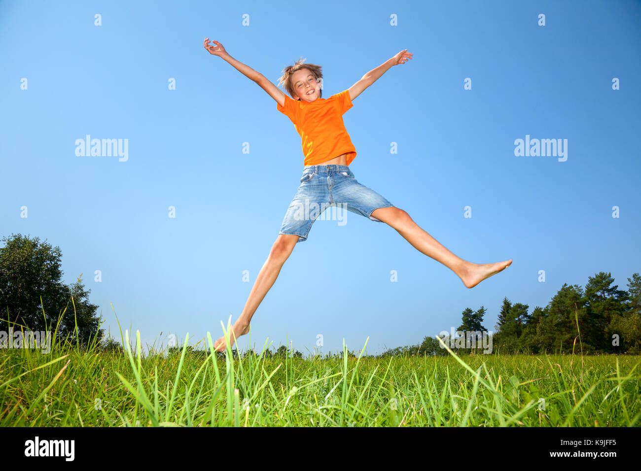 Kid jumping on the Sunny meadow en un été Banque D'Images