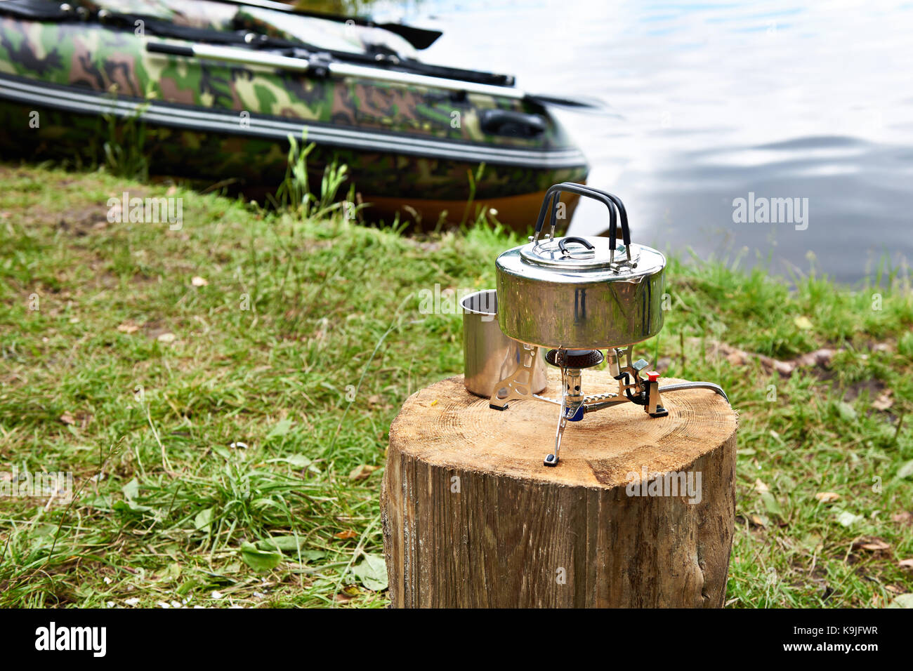 La randonnée avec un poêle électrique sur une souche et un bateau de pêche sur le fond d'un lac Banque D'Images