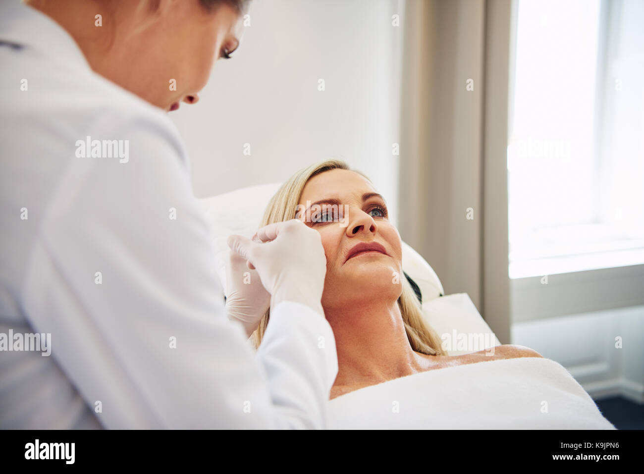 Femme médecin d'administrer des injections de botox sur le visage d'une femme mature est posé sur une table dans une clinique de beauté Banque D'Images