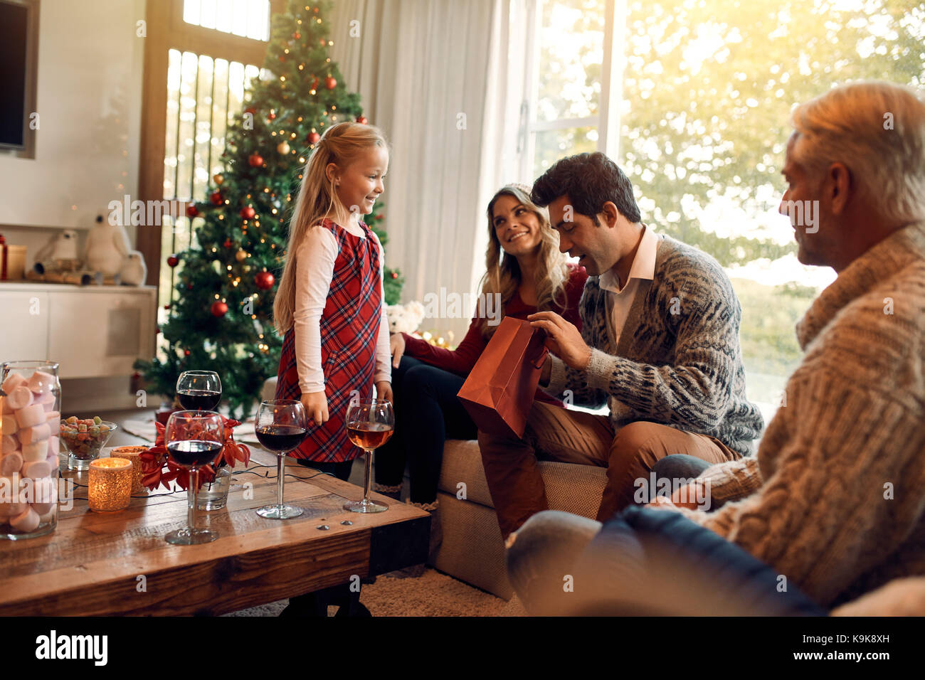 Jeune homme d'ouvrir les cadeaux de Noël de sa fille. Caucasian family in living room sur un échange de cadeaux la veille de Noël. Banque D'Images