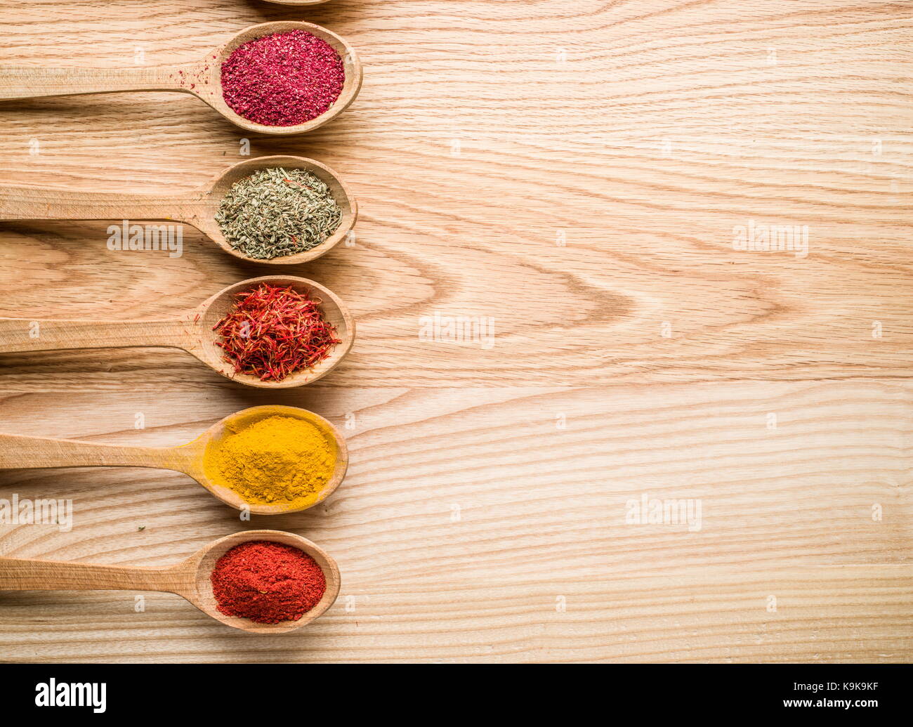 Assortiment d'épices colorées dans l'cuillères en bois sur la table en bois. Banque D'Images