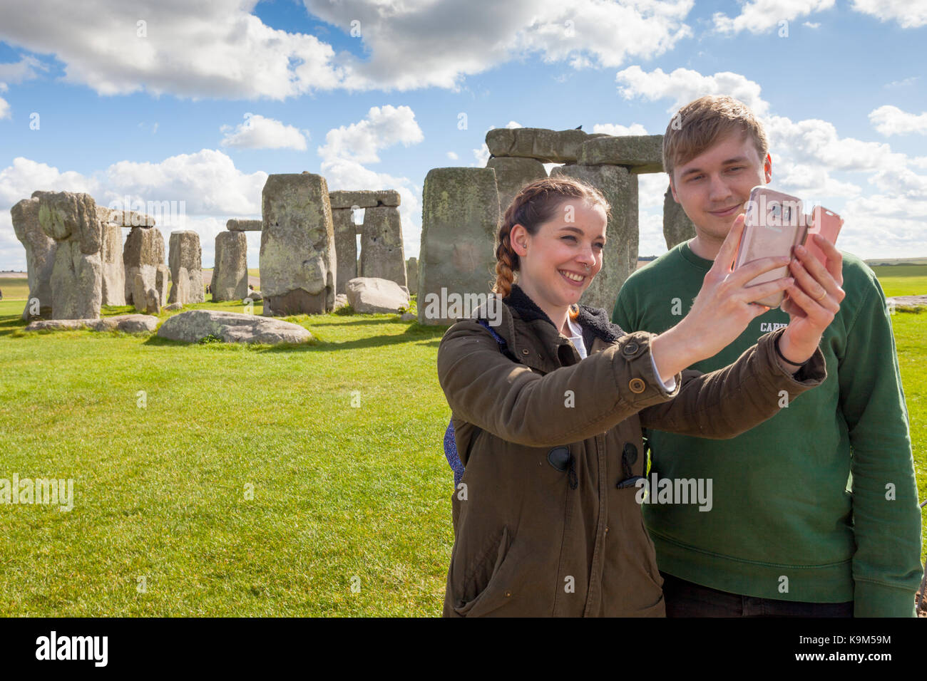 Jeune couple en prenant une photographie selfies en face du site du patrimoine mondial de Stonehenge Wiltshire, UK Banque D'Images