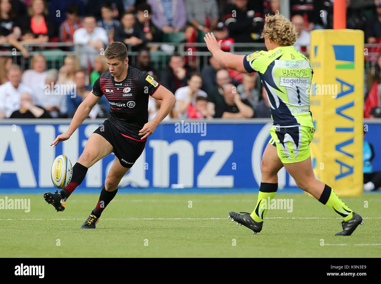 Owen farrell des Saracens kicks avant comme sale sharks' ross harrison ressemble à bloquer pendant le match aviva premiership à barnet copthall, Londres. Banque D'Images