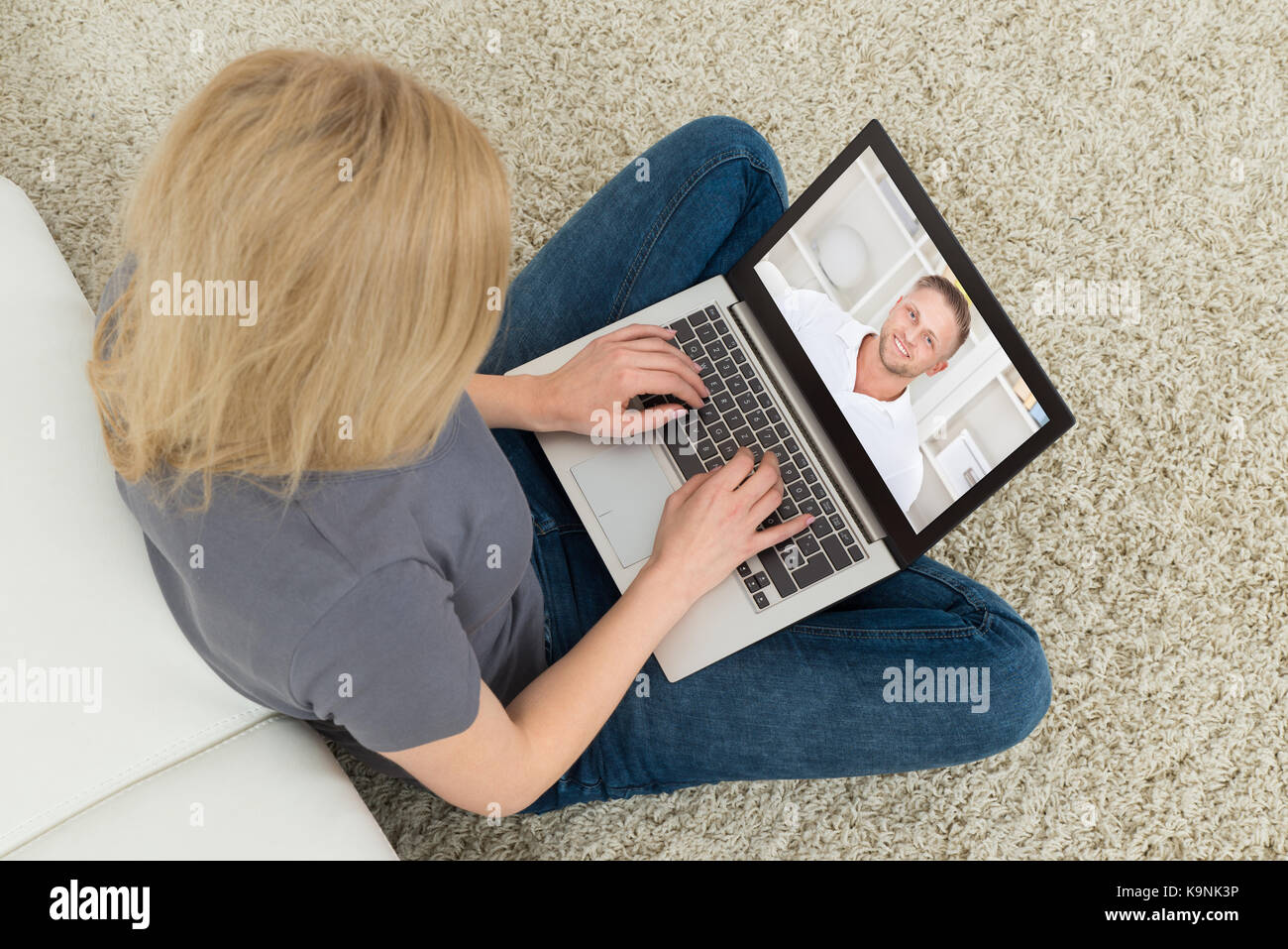 Jeune femme chat vidéo en ligne avec l'homme sur l'ordinateur portable dans la salle de séjour Banque D'Images