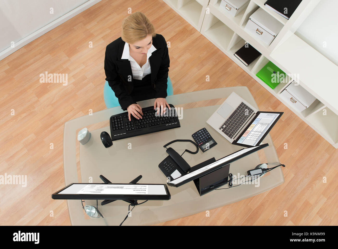 Young Businesswoman Sitting on Fitness Ball tout en travaillant sur Computer in Office Banque D'Images