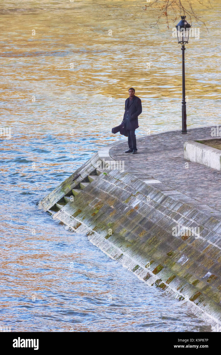 France, Paris - printemps 2008 : un musicien solitaire avec une guitare se tient sur le quai de bourbon de la seine près de la place Louis Aragon à paris. fr Banque D'Images