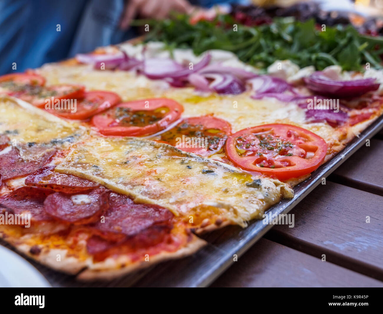 Pizza à croûte mince avec de multiples garnitures (pepperoni, fromage, tomate, oignon, roquette) présentés dans une façon unique Banque D'Images